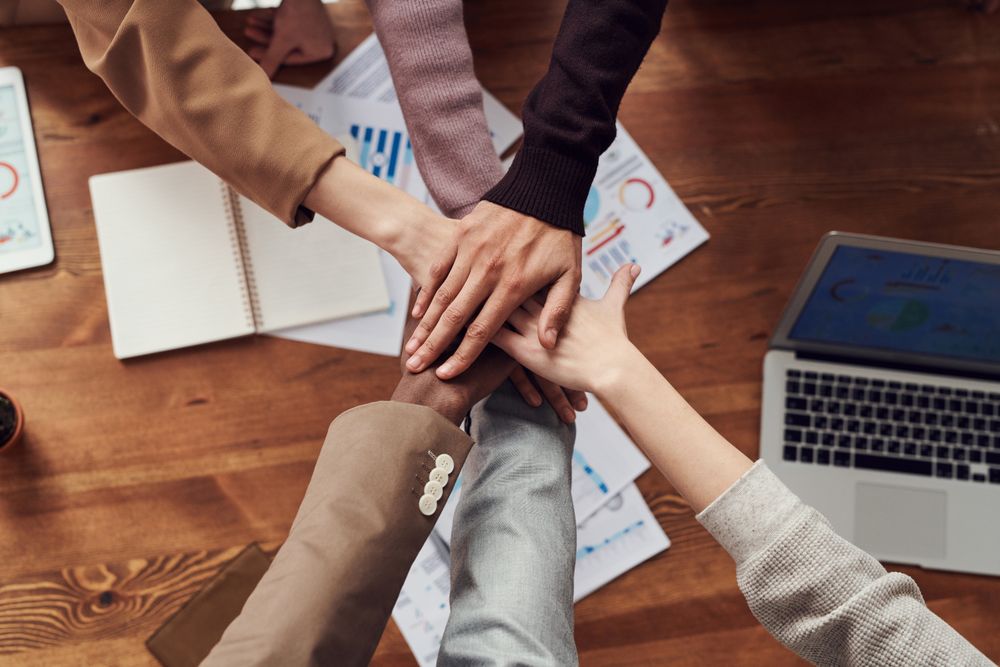 Equipe reunida ao redor de uma mesa, trabalhando em conjunto com um notebook e anotações